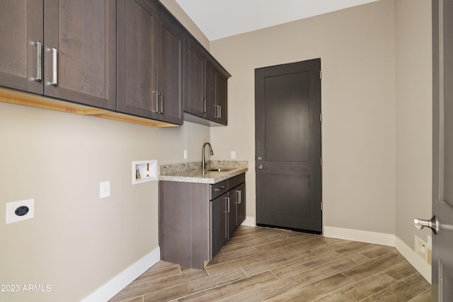 kitchen with light hardwood / wood-style floors, light stone countertops, dark brown cabinetry, and sink