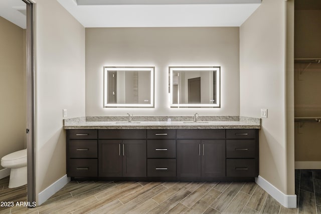 bathroom with hardwood / wood-style floors, toilet, and dual bowl vanity