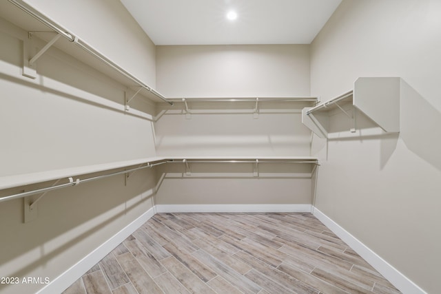 walk in closet with light hardwood / wood-style floors