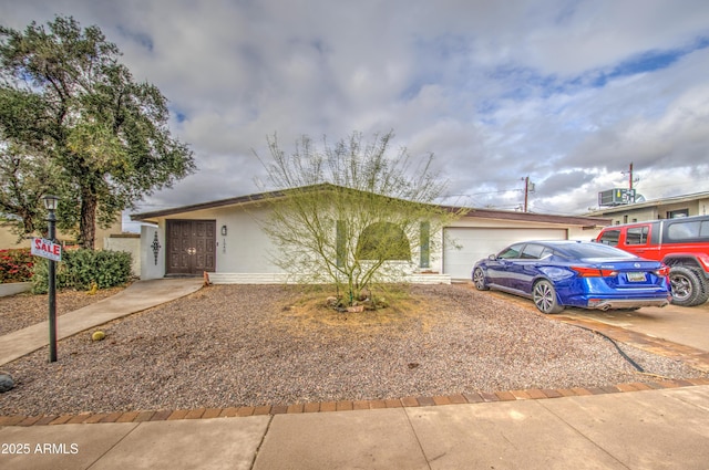 ranch-style home featuring a garage, concrete driveway, and stucco siding