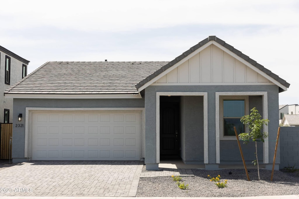 view of front of home with board and batten siding, decorative driveway, and stucco siding