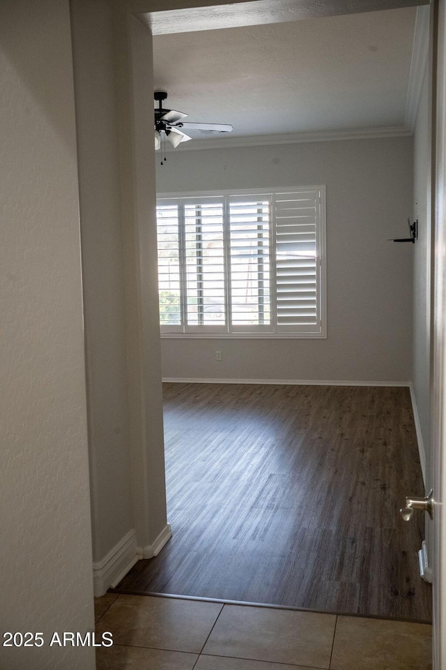 empty room featuring crown molding, dark tile patterned flooring, and ceiling fan