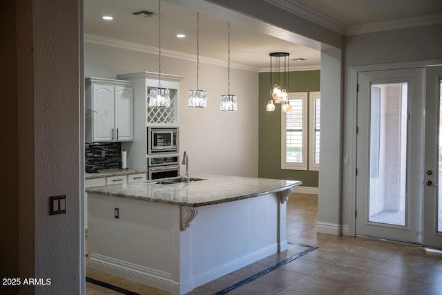 kitchen with tasteful backsplash, white cabinetry, sink, a kitchen island with sink, and stainless steel appliances