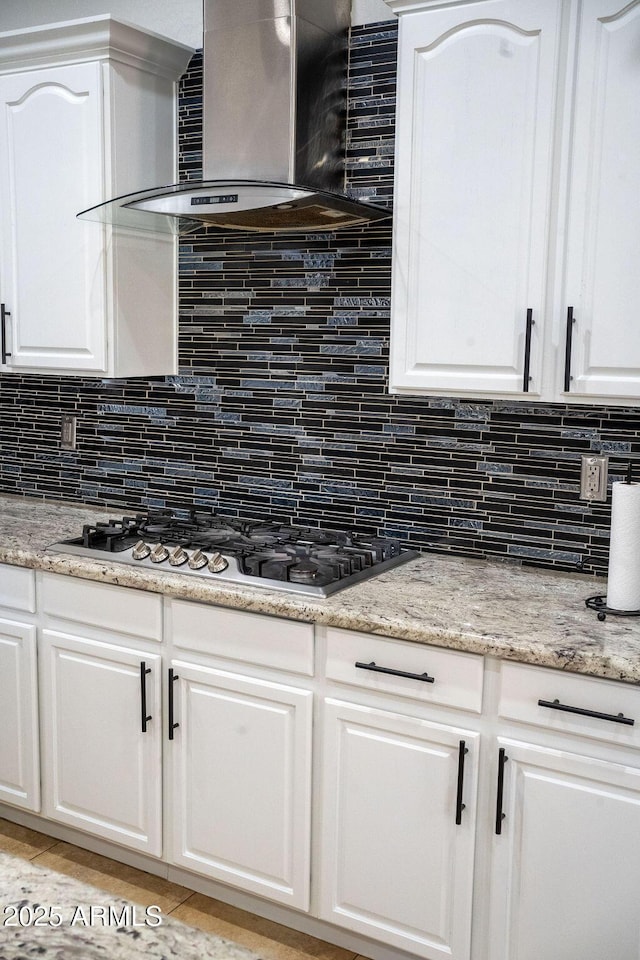 kitchen with white cabinetry, wall chimney range hood, and backsplash