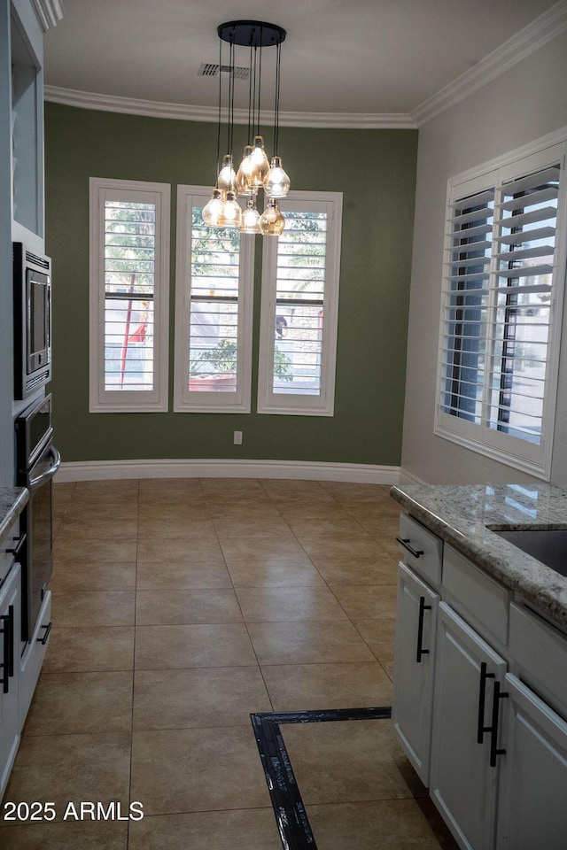 kitchen featuring pendant lighting, light tile patterned floors, appliances with stainless steel finishes, a notable chandelier, and white cabinets