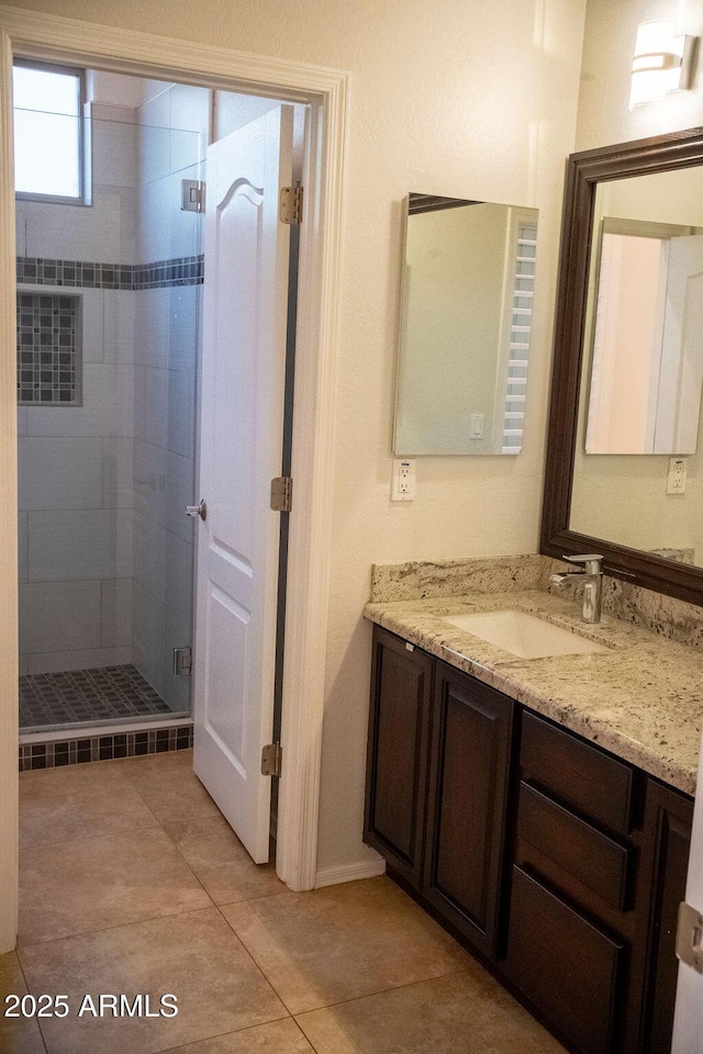 bathroom with vanity, a shower with shower door, and tile patterned floors