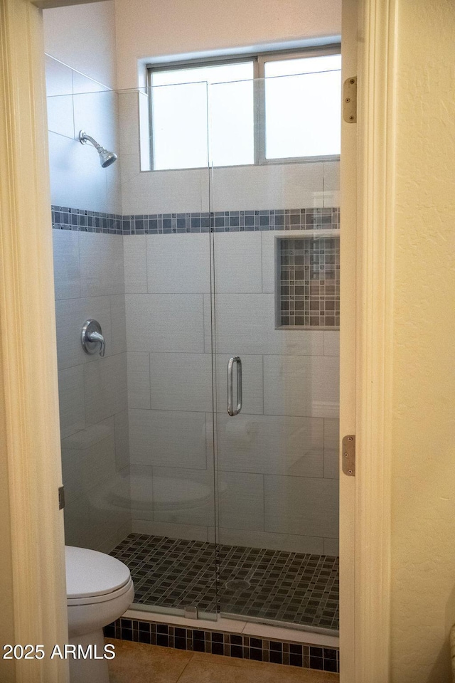 bathroom featuring tile patterned floors, toilet, and walk in shower