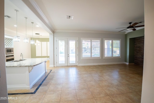 kitchen featuring appliances with stainless steel finishes, sink, hanging light fixtures, light tile patterned floors, and light stone countertops