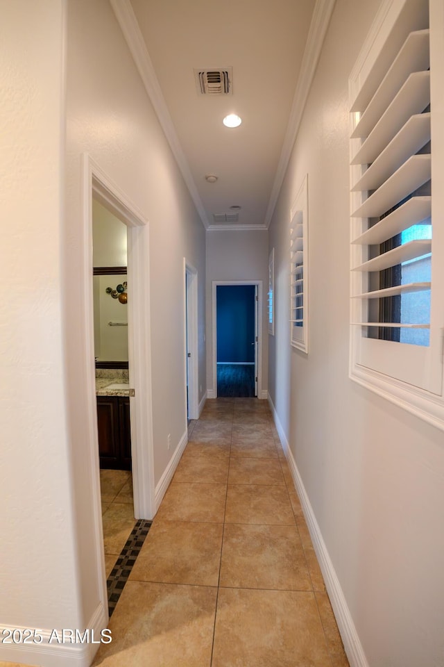 corridor featuring light tile patterned floors and crown molding