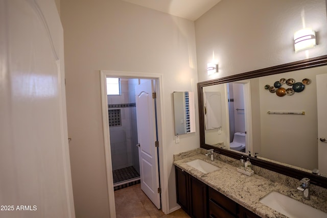 bathroom featuring tile patterned floors, vanity, toilet, and a tile shower