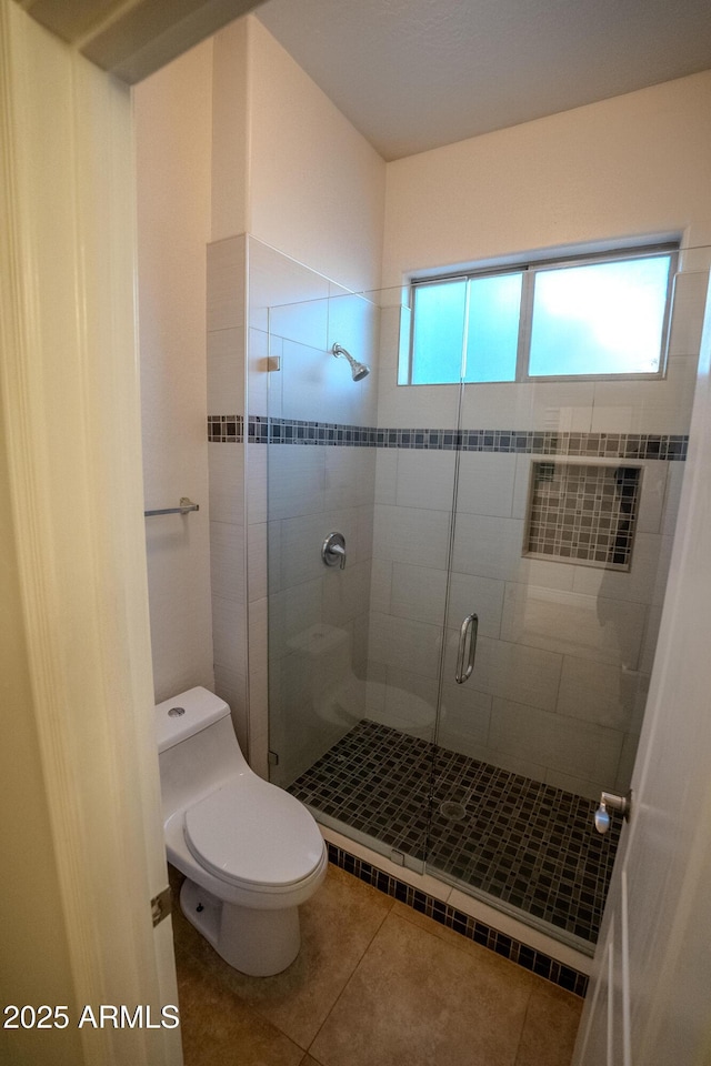 bathroom with tile patterned flooring, toilet, and walk in shower