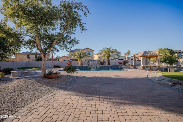 view of front facade featuring a fenced in pool, a fire pit, a gazebo, a patio area, and pool water feature