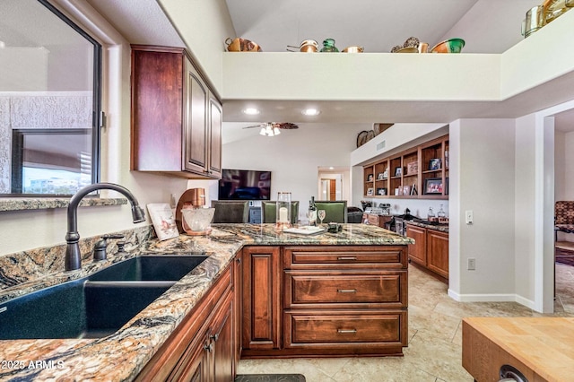 kitchen with lofted ceiling, a peninsula, stone countertops, a ceiling fan, and a sink