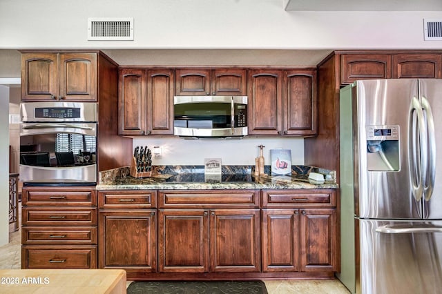 kitchen with dark stone counters, visible vents, and appliances with stainless steel finishes