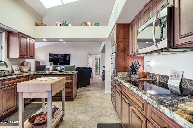 kitchen featuring open floor plan, vaulted ceiling, a peninsula, stainless steel appliances, and a sink