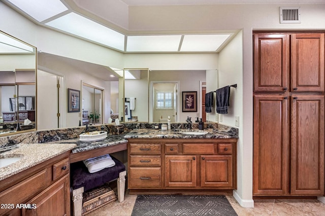 bathroom featuring tile patterned flooring, double vanity, visible vents, and a sink