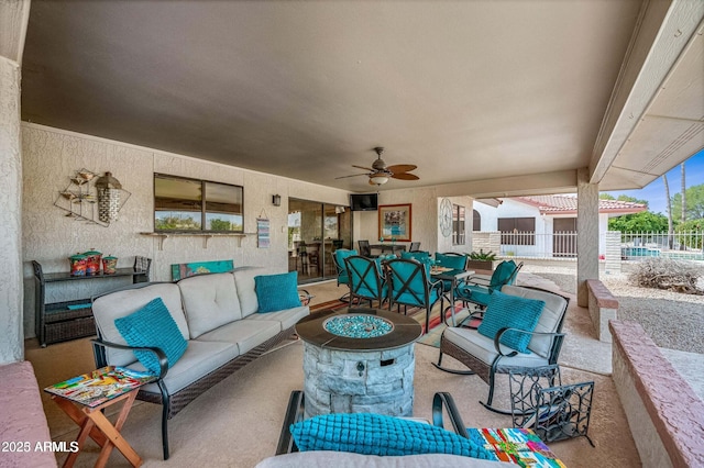 view of patio with an outdoor living space with a fire pit, outdoor dining space, a ceiling fan, and fence