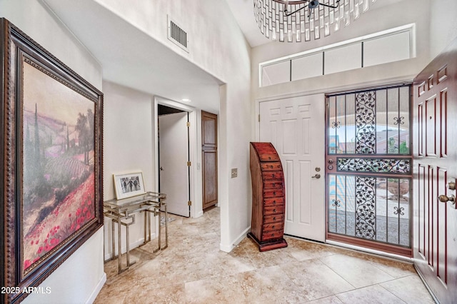 entrance foyer featuring baseboards, visible vents, and a towering ceiling