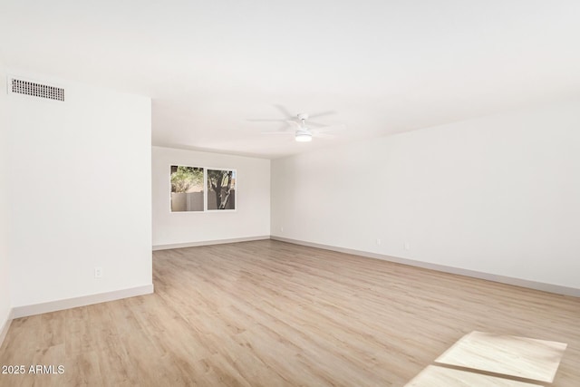 spare room with a ceiling fan, visible vents, baseboards, and wood finished floors