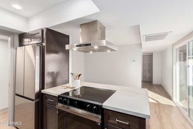 kitchen with electric range, visible vents, dark brown cabinets, freestanding refrigerator, and range hood