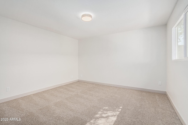 carpeted spare room featuring baseboards