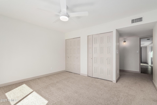 unfurnished bedroom with multiple closets, baseboards, visible vents, and carpet flooring