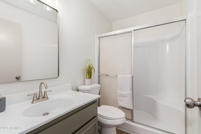 bathroom with a stall shower, vanity, and toilet