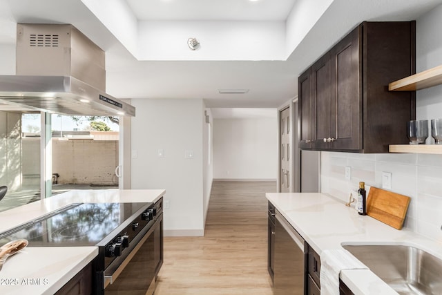 kitchen with dark brown cabinetry, wall chimney exhaust hood, black electric range oven, open shelves, and stainless steel dishwasher