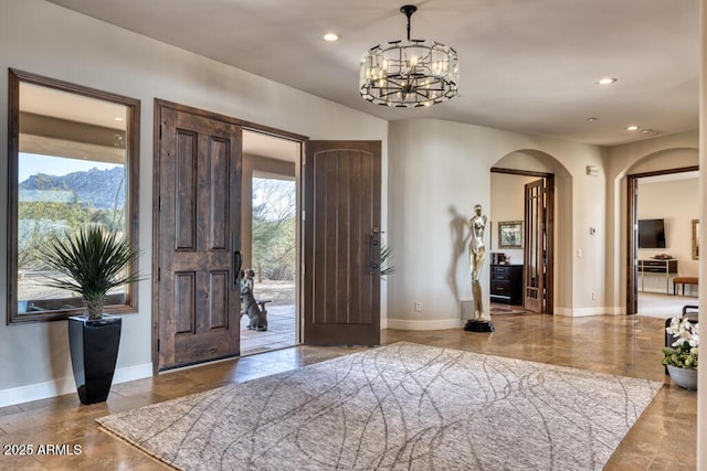 entrance foyer featuring recessed lighting, baseboards, arched walkways, and an inviting chandelier