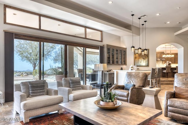 living area with recessed lighting, visible vents, arched walkways, and a notable chandelier