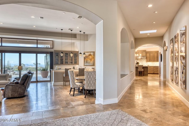 hallway featuring stone tile floors, visible vents, recessed lighting, and baseboards