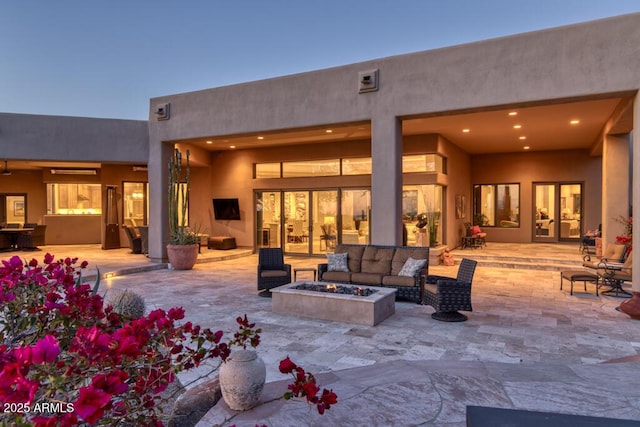 back of house with an outdoor living space with a fire pit, a patio area, and stucco siding