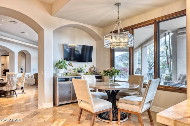 dining space featuring a chandelier, arched walkways, and baseboards