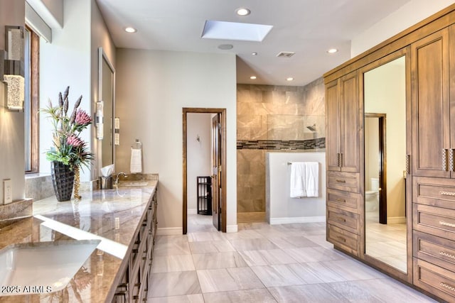 bathroom featuring visible vents, walk in shower, double vanity, a skylight, and a sink