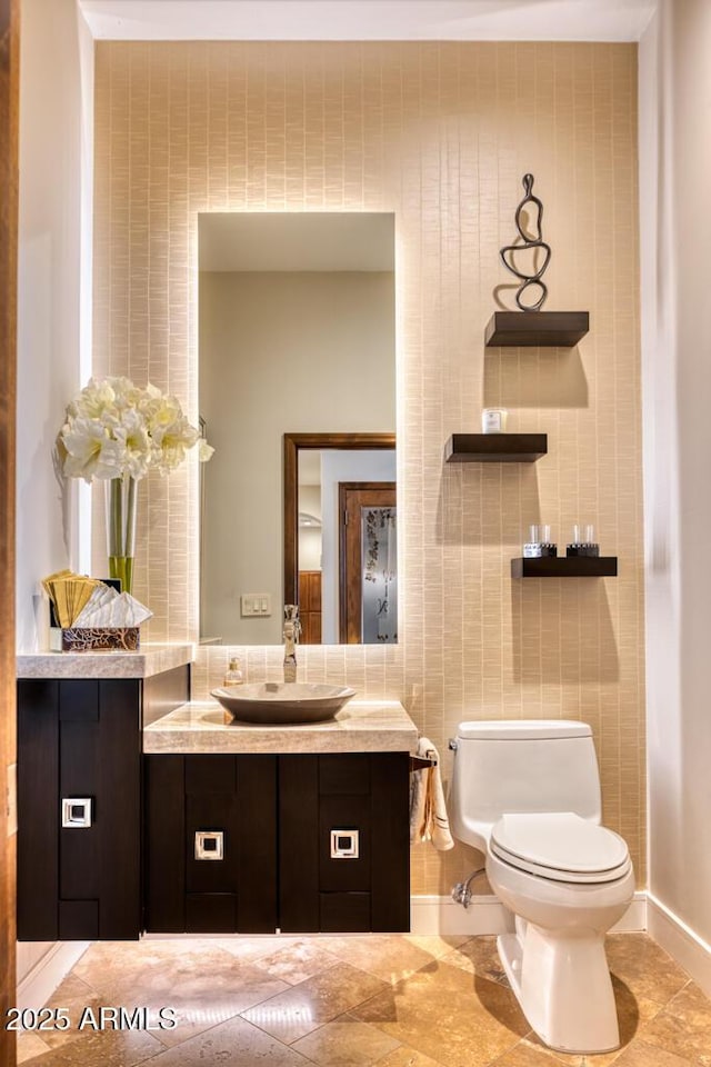 bathroom featuring vanity, tile walls, toilet, and baseboards