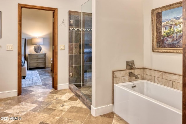 bathroom with connected bathroom, baseboards, a bath, and a shower stall