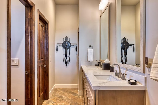 full bath featuring double vanity, baseboards, and a sink