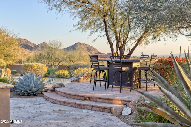 patio terrace at dusk with a mountain view and outdoor dry bar