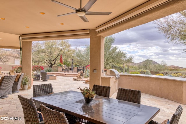 view of patio / terrace featuring grilling area, fence, outdoor dining space, an outdoor kitchen, and a ceiling fan