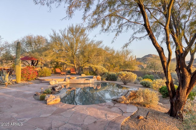 view of pool featuring an in ground hot tub, a patio area, and a mountain view