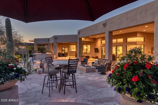 patio terrace at dusk featuring outdoor dry bar and an outdoor fire pit