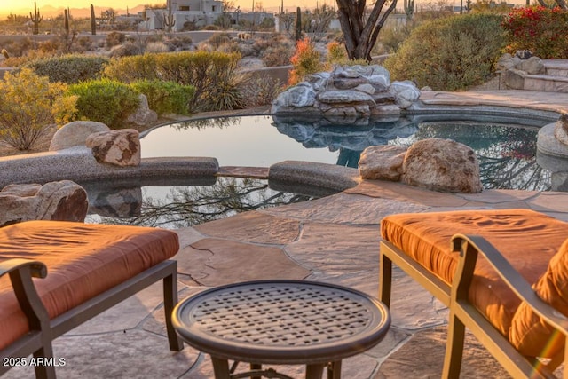 pool at dusk with a hot tub