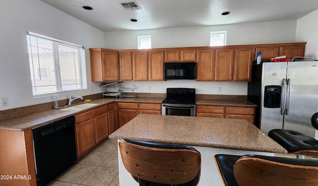 kitchen with light tile patterned flooring, a wealth of natural light, sink, and black appliances