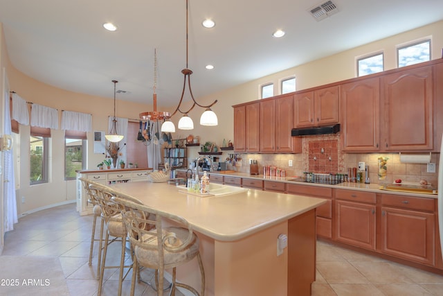 kitchen featuring a center island, pendant lighting, light countertops, and visible vents