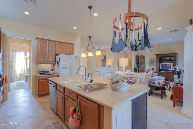 kitchen featuring visible vents, an island with sink, light countertops, white fridge with ice dispenser, and a sink