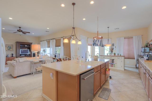 kitchen with a center island with sink, a wealth of natural light, light countertops, stainless steel dishwasher, and open floor plan