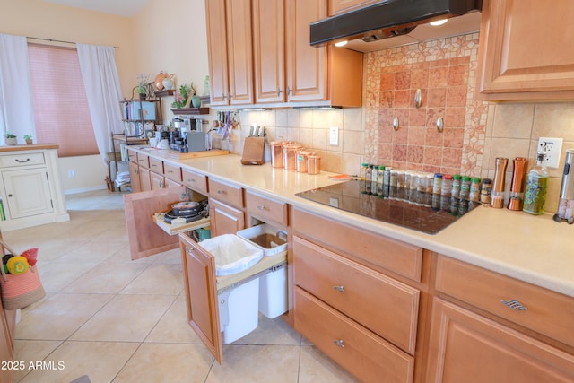 kitchen with light countertops, under cabinet range hood, black electric stovetop, and light tile patterned floors