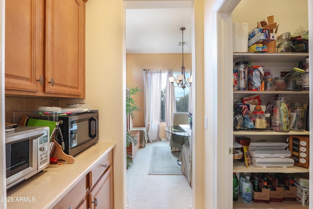 interior space featuring a chandelier, light countertops, hanging light fixtures, and stainless steel microwave