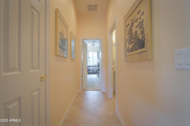 corridor with light tile patterned flooring, visible vents, and baseboards