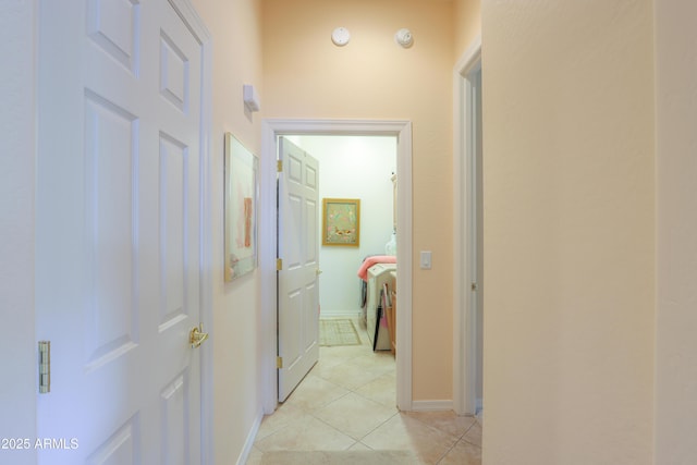 hall featuring light tile patterned floors, baseboards, and washer / dryer